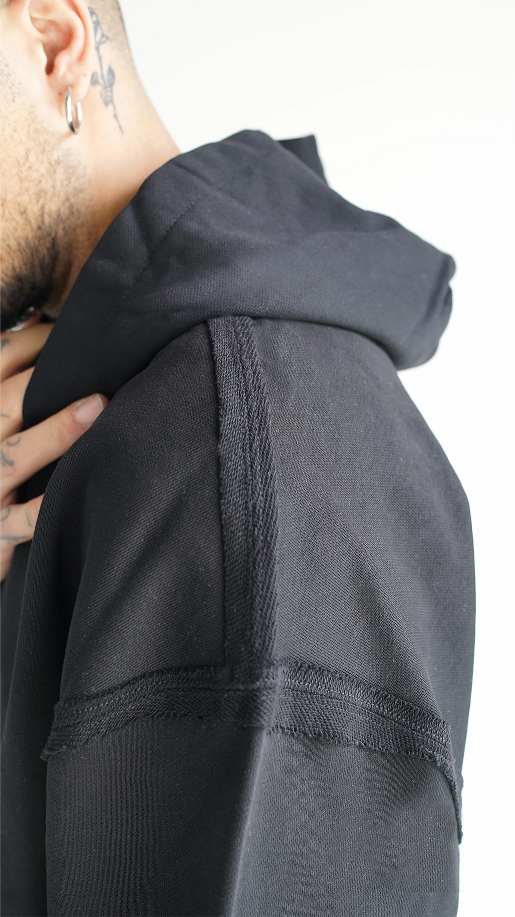 Dettaglio del cappuccio oversize strutturato con cuciture a rovescio a vista e bordi raw su felpa Empyrom