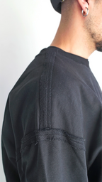 Dettaglio delle cuciture a rovescio esposte e del logo ricamato nero su felpa oversize Empyrom