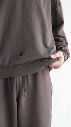 Dettaglio ravvicinato delle cuciture a rovescio esposte e dei bordi a taglio vivo sulla hoodie marrone Empyrom