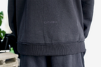 Dettaglio delle cuciture a rovescio esposte e del logo ricamato nero su felpa oversize Empyrom