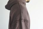 Dettaglio ravvicinato delle cuciture a rovescio esposte e dei bordi a taglio vivo sulla hoodie marrone Empyrom