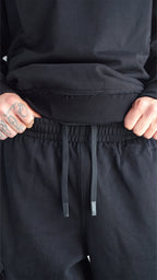 Dettaglio dei tasconi laterali e delle cuciture a rovescio sulle ginocchia dei pantaloni cargo della tuta Empyrom